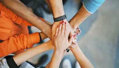 Overhead view of a group of people stacking hands together in a gesture of teamwork and unity.